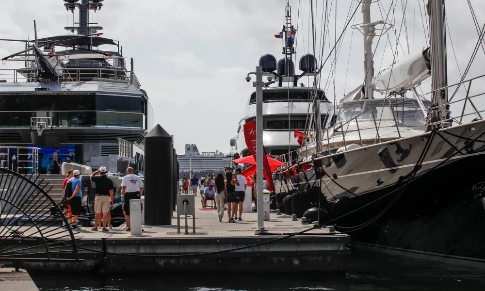 Visitors walking the docks at the boat show surrounded by multiple mega-yachts